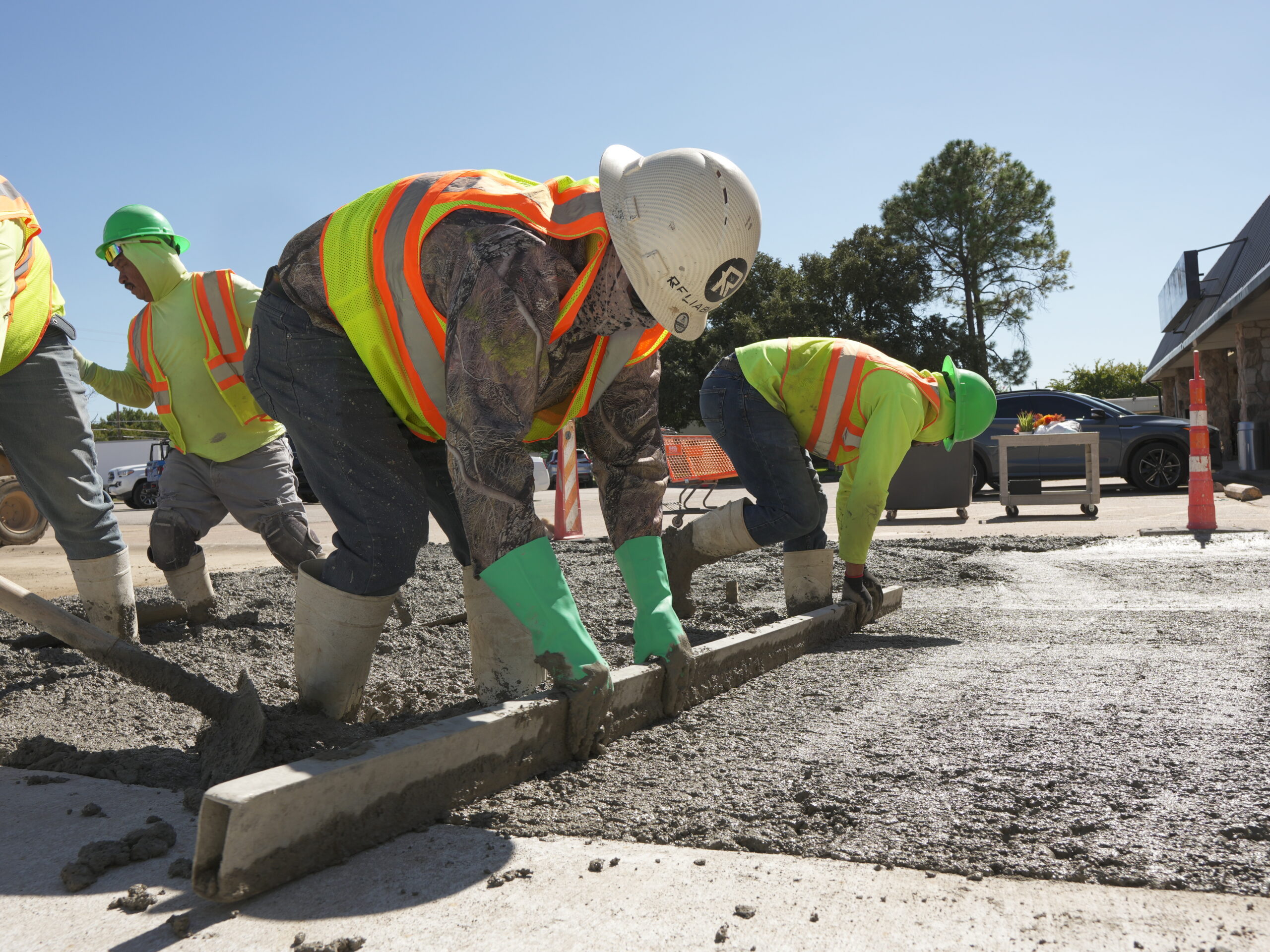 Reliable Paving crew finishing a fresh concrete pour on a commercial parking lot in Texas