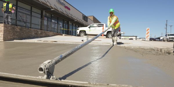 Reliable Paving crew pouring and hand-finishing a concrete parking lot outside a North Texas retail center